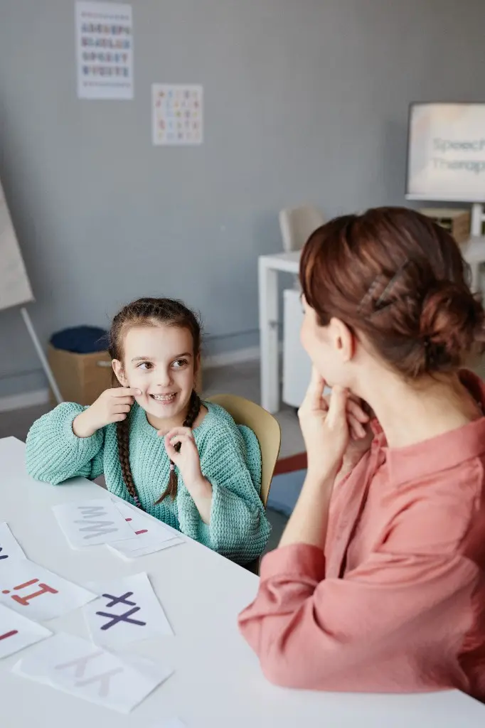 Young girl and clinician doing letter exercises together at a table